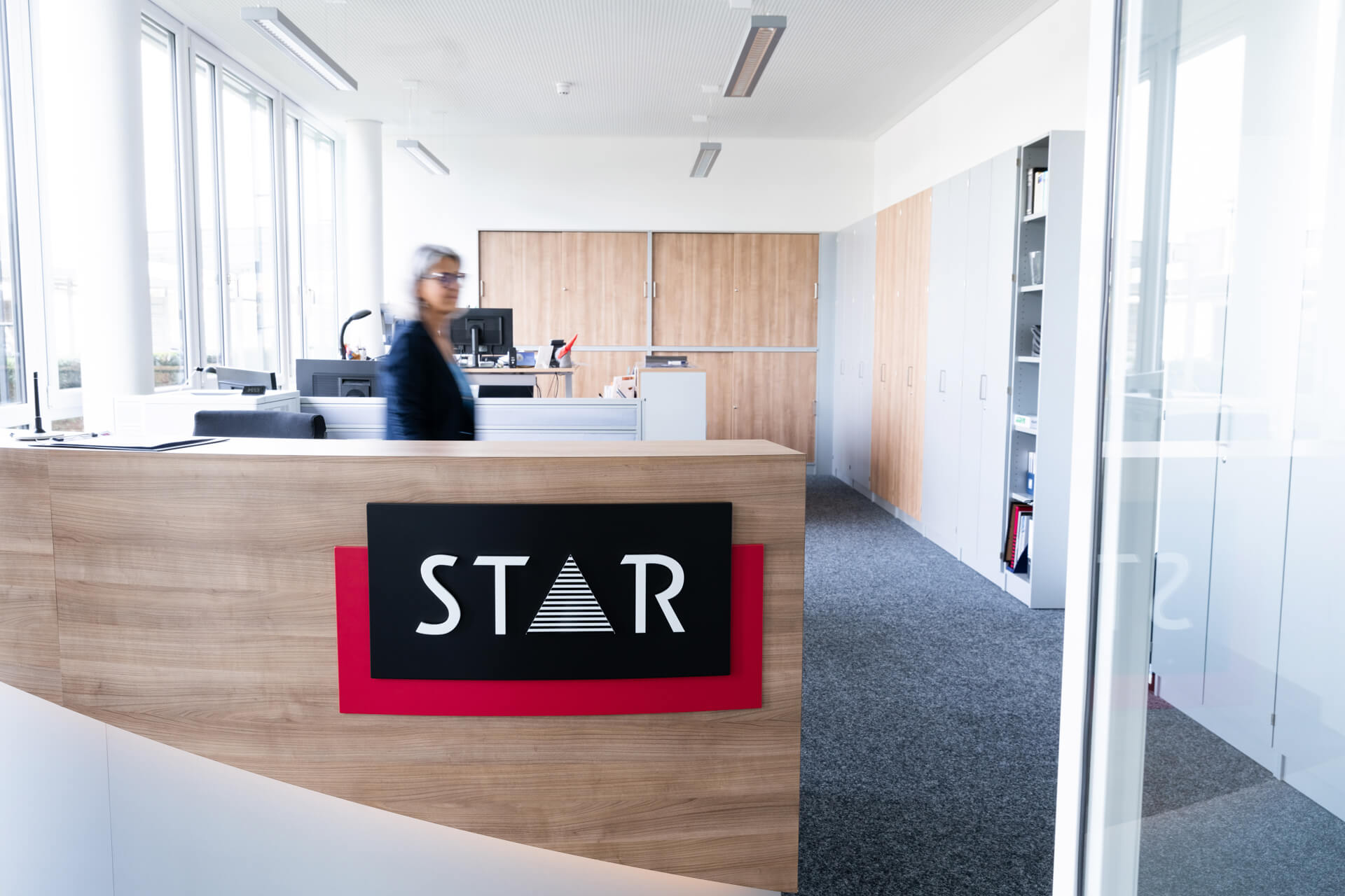 STAR Empfang mit großem STAR Logo und Mitarbeiterin in Bewegung.