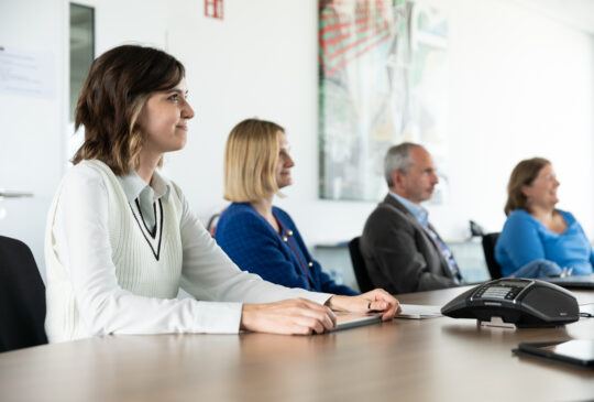 Four project managers sitting at a conference table in a meeting about quality and information security.