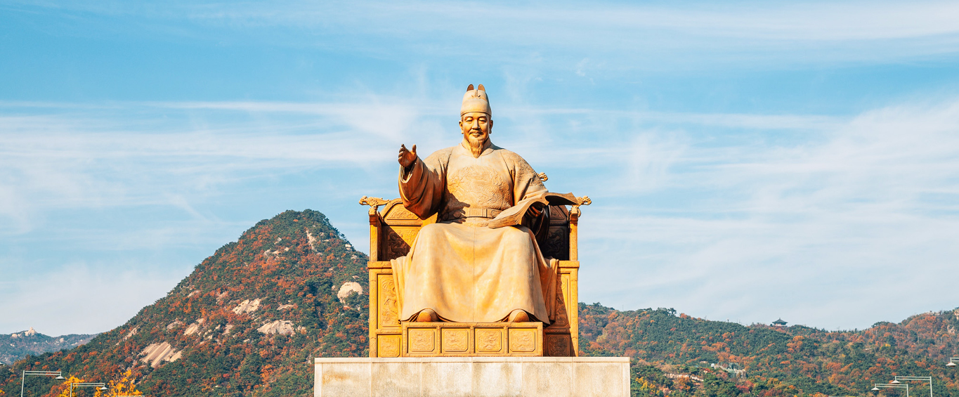 Statue of King Sejong the Great in front of a mountainous landscape in Seoul, South Korea; he is considered the creator of the Korean alphabet Hangeul.