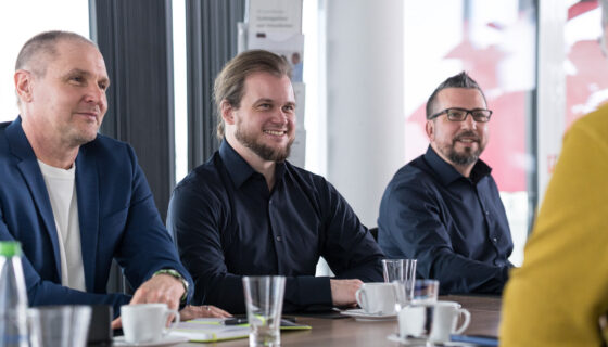Teilnehmende sitzen an einem Tisch und besprechen Inhalte der technischen Dokumentation.