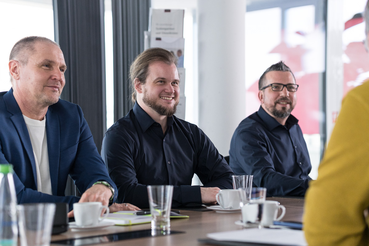 Teilnehmende sitzen an einem Tisch und besprechen Inhalte der technischen Dokumentation.