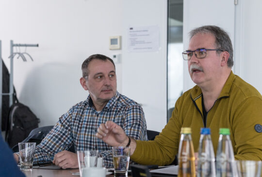 Personen sitzen an einem Konferenztisch und besprechen Inhalte zur technischen Dokumentation.