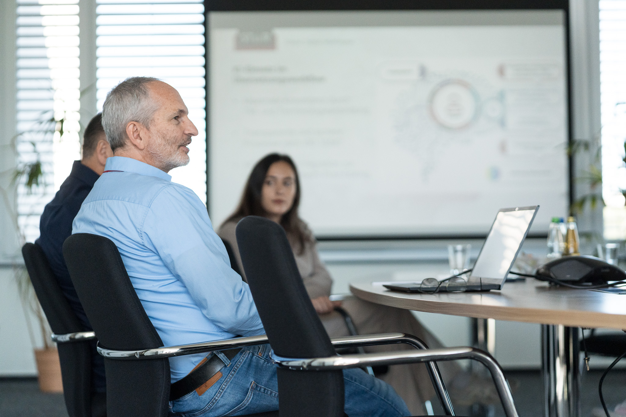 People sitting in a meeting room watching a presentation projected on a screen.