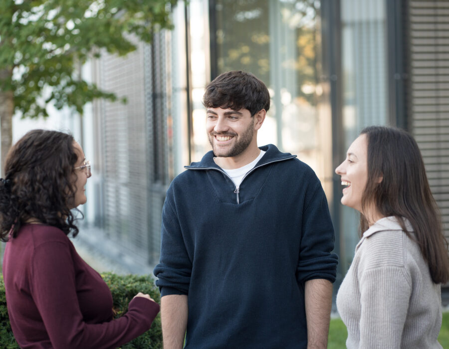 Three people standing outside a building having a conversation.